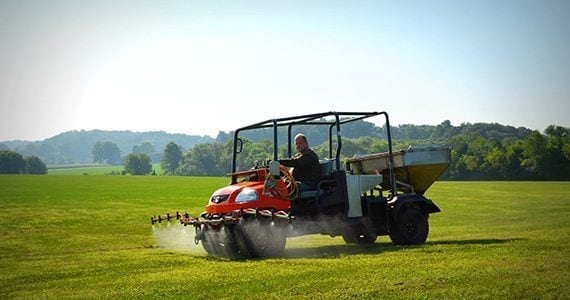 Licensed technician spraying preventative grub control on a Pennsylvania lawn